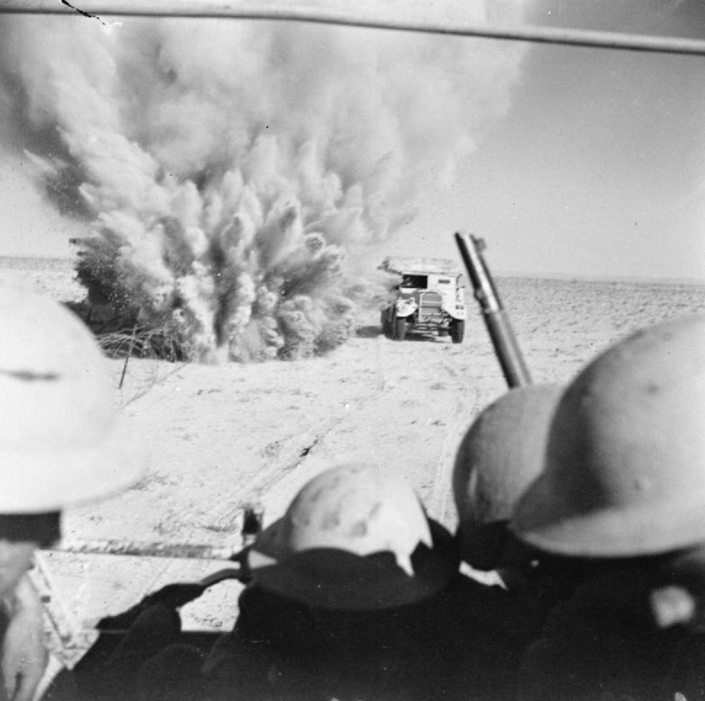 A mine explodes close to a British artillery tractor as it advances through enemy minefields and wire to the new front line.